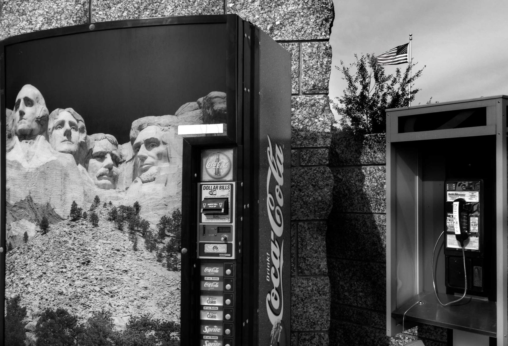 Auto America photo series. Mount Rushmore South Dakota with Coke A Cola machine, public telephone,USA flag : THOUGHTS of the MOMENT : Salem Krieger